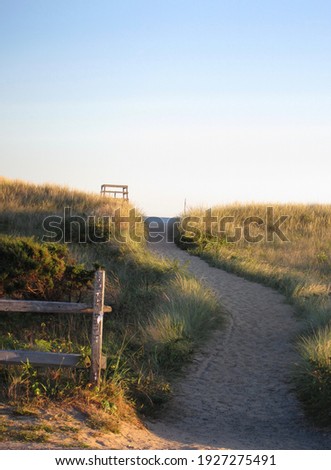 At the beach: path to top of grassy dune and tip of lifeguard chair, sliver of sea in distance; Martha's Vineyard