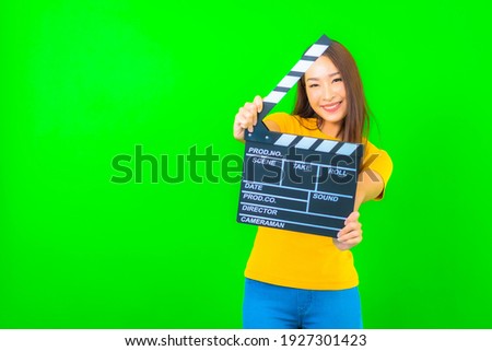 Portrait beautiful young asian woman with movie clapper on green isolated background