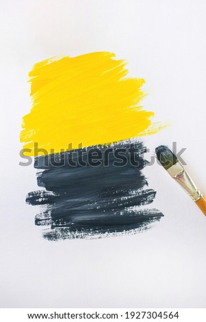 Brush for painting on the background of abstract gouache paintings in yellow and gray colors. Brushstrokes on canvas. Color 2021.