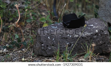 A Black Camera Hood On A Stone From A Jungle
