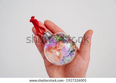 Toy ball for Christmas tree with kid girl photo in hand. original decoration and gift for the new year. Souvenirs.