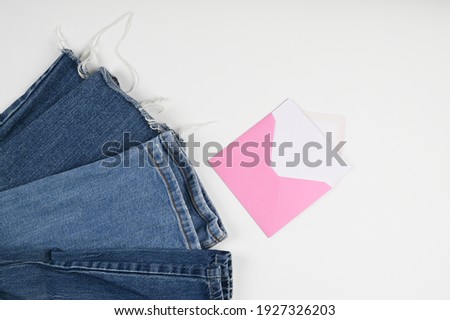 Cropped view of denim Jeans and pink envelope with blank card isolated on white. Shopping and sales concept. High quality photo