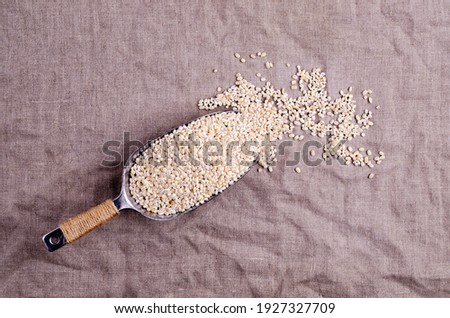 Dry pearl barley in a metal scoop on a textile background. Top view. Selective focus.