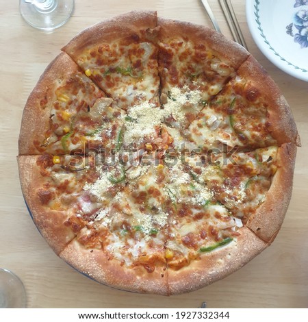 A pizza divided into eight pieces is placed on the table. Picture of the meal table