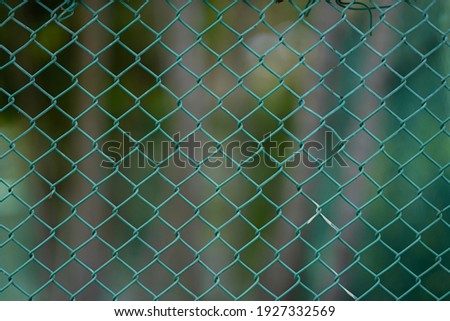 Close up of green wire fence or metal net with natural green leaves background.