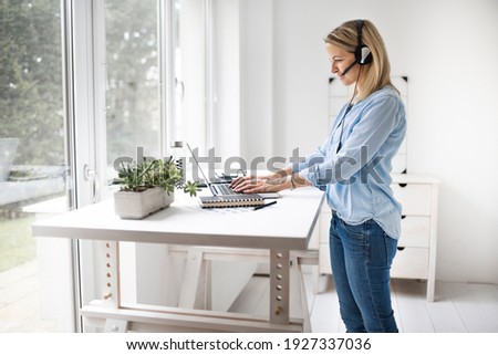 Fit Businesswoman working at ergonomic standing desk Royalty-Free Stock Photo #1927337036