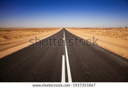 Empty open outback road in South Australia. Straight single lane asphalt road stretching into the distance. Desert scene with a pure blue cloudless sky. Endless travel and adventure. Royalty-Free Stock Photo #1927355867