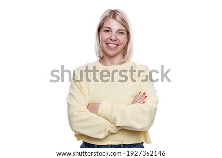 Laughing young woman with arms crossed on goudy. Blonde in a yellow sweater and jeans. Isolated on a white background.