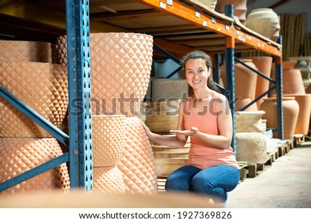 Female seller is standing near clay pots in stock. High quality photo
