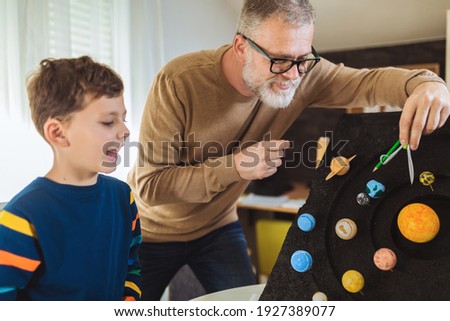Happy school boy and his father making a solar system for a school science project at home