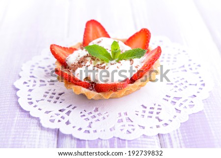 Tasty tartlet with strawberries on table close-up