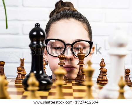 A teenage girl plays chess. Board game.