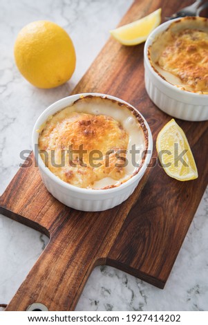 Traditional Eastern Germany DDR GDR cuisine -Würzfleisch or Ragout Fin a pork and poultry meat meal in light roux  sauce with cheese gratin and lemon on wooden board and light marble background