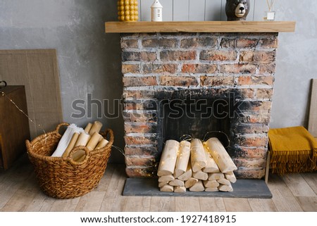 Scandinavian interior with red brick fireplace, wicker basket for firewood, pile of logs for a fire