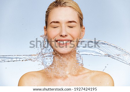 Photo of  young  woman with clean skin and splash of water. Portrait of smiling woman with drops of water around her face. Spa treatment. Girl washing her body with water. Water and body. Royalty-Free Stock Photo #1927424195
