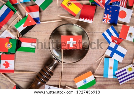 Swiss flag. Economic growth, Imports and Exports, Armaments and Security concept. Magnifying glass and flags of different countries