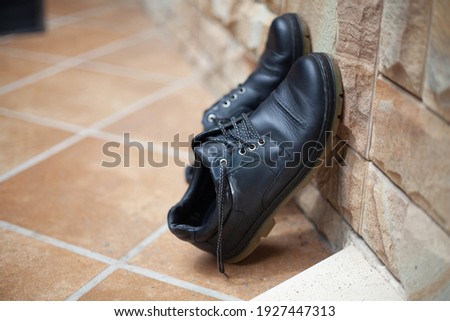 Drying shoes naturally. A pair of shoes stands upright and rests on a stone fence. Bottom tile


