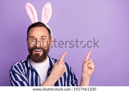 Photo of shocked surprised mature man point, finger empty space wear rabbit ears headband isolated over purple color background