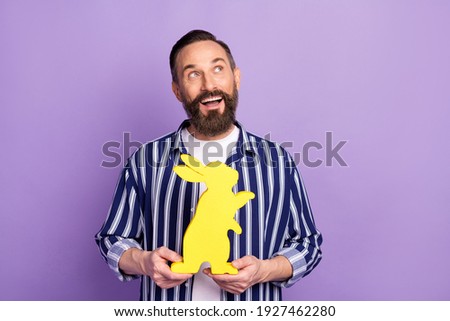 Photo of minded mature man hold easter rabbit look copyspace isolated over violet color background