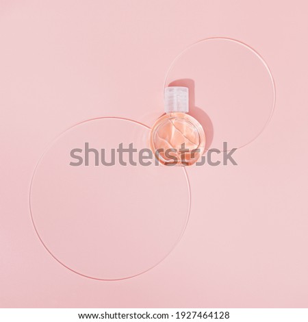 Small cosmetic bottle for cream or gel designed with circular disks. Beauty product package, mock up plastic container on pastel pink background. Top view.
