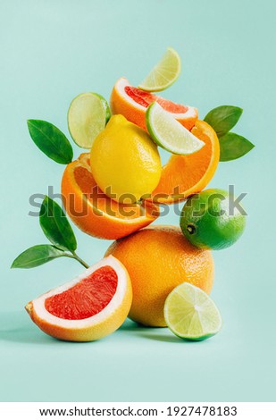 pyramid of citrus grapefruit, lemon, orange and lime decorated with leaves on a blue background Royalty-Free Stock Photo #1927478183