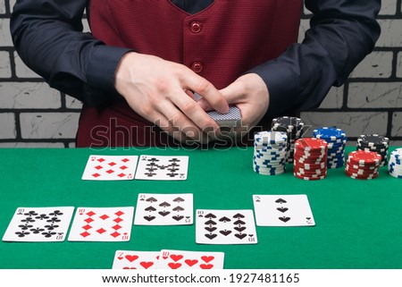 the dealer at the green poker table deals the last card of the game