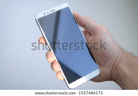 White smartphone in hand with black display. Phone in hand with blank screen.