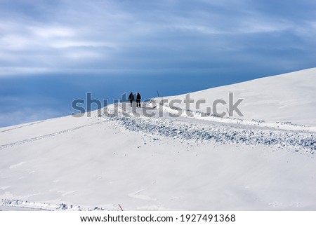 Two hikers on a snowy footpath in winter landscape. Lessinia High Plateau (Altopiano della Lessinia), Regional Natural Park, Verona Province, Veneto, Italy, Europe.