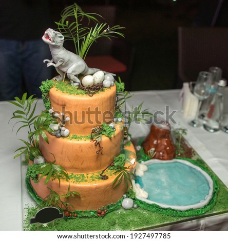 Children's holiday white cake decorated with mastic figurines of dinosaurs in the Jurassic period jungle. Concept ideas desserts for kids