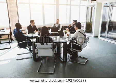 Group of young business people working and communicating while sitting at the office desk together with colleagues sitting. business meeting Royalty-Free Stock Photo #1927500299