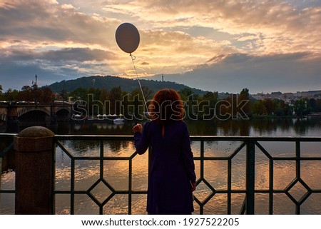 girl with balloon watching the sunset over the Vltava river in Prague, Czech Republic Royalty-Free Stock Photo #1927522205