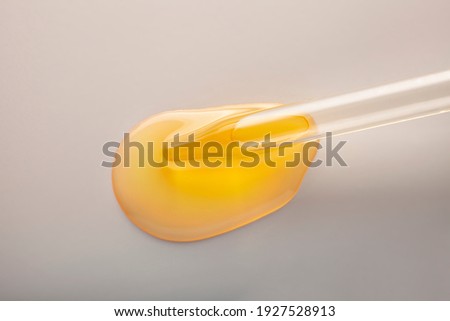 Cosmetic oil drop with pipette on a gray background