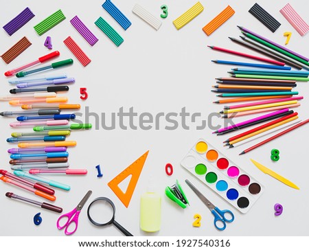Bright still life scene of stationery on a white background. Colored pencils, felt-tip pens, plasticine and paints, flat lay with a place for text.