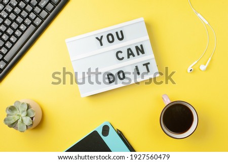 You can do it - text on display lightbox on yellow workplace background. Motivational words.