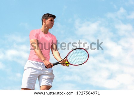Young handsome tennis player with racket and ball prepares to serve at beginning of game or match. Beautiful colorful sports background, banner with copy space Royalty-Free Stock Photo #1927584971