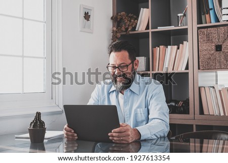 Happy young caucasian businessman smiling working online watching webinar podcast on laptop and learning education course conference calling make notes sit at work desk, elearning concept