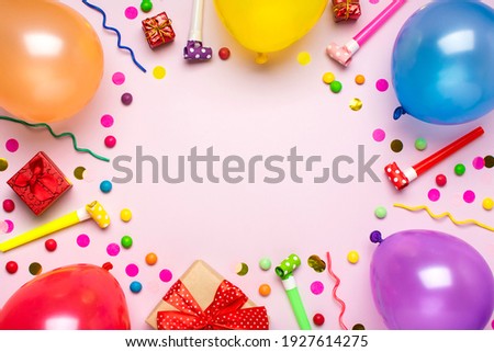 Colorful party frame with red gift box with various party confetti, balloons, streamers, pokers and decorations on pink background. Holiday card Flat lay Top view Happy Birthday party concept