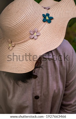 Close-up of a pink hat covering the face of young girl with casual dress