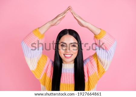 Photo of young happy cheerful smiling asian girl hold hands above head roof new house isolated on pink color background
