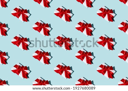 Gift pattern. Blue seamless background. Special day congratulation design. Holiday bonus. Symmetrical composition of white boxes with red ribbon bows isolated on light color.
