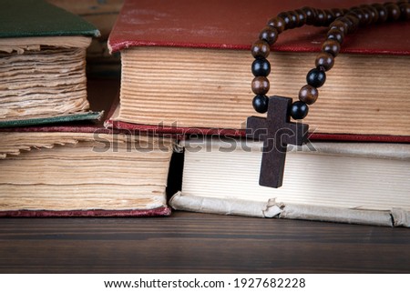 Stack of books and wooden cross. Religion, prejudice, prohibition and faith concept Royalty-Free Stock Photo #1927682228