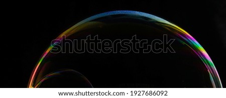 macro photograph of soap bubble on black background with rainbow colors 