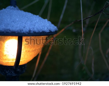 Garden lantern covered in snow in winter close up