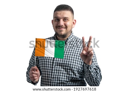 White guy holding a flag of Cote d'Ivoire and shows two fingers isolated on a white background.