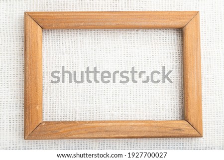 Wooden frame on smooth white linen tissue. Top view, flat lay, natural textile background and texture.