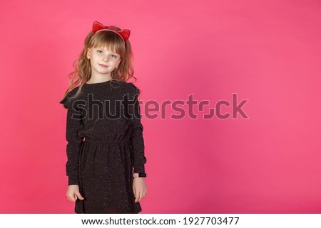 Portrait 6-7 year old girl in black dress on pink isolated background looks at camera. Concept Playing and Children Celebrities. Little child in style clothes posing and showing emotions. Copy space