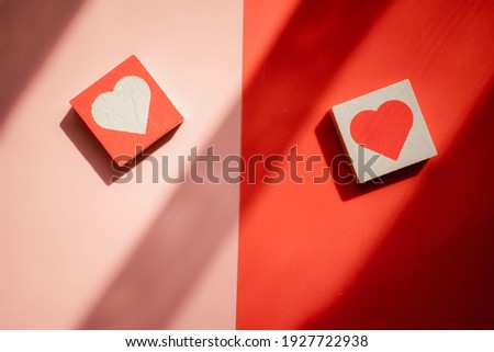 Wood heart shape block on red and pink background in morning lighting. Concept background of love expression