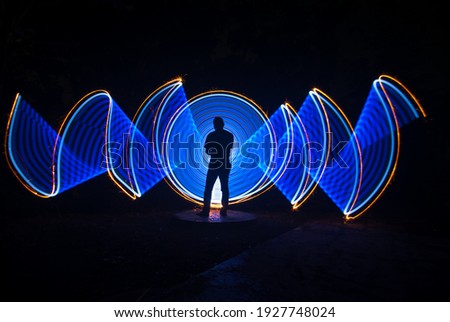 one person standing against beautiful white and blue circle light painting as the backdrop
