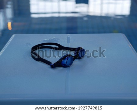 Plastic swimming goggles on the nightstand for the start in the swimming pool. Building for sports.