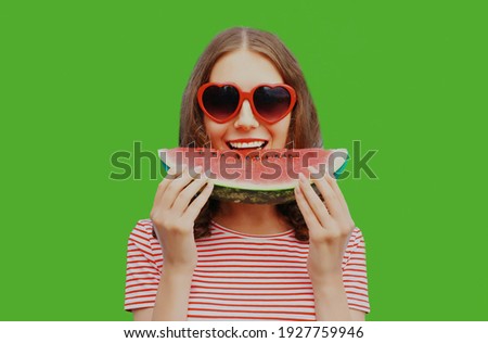 Portrait of happy smiling young woman with slice of watermelon on a green background